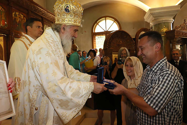 Патриарх сербский Ириней вручает плакету семейной паре