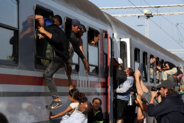 Мигранты залезают в вагоны поезда
